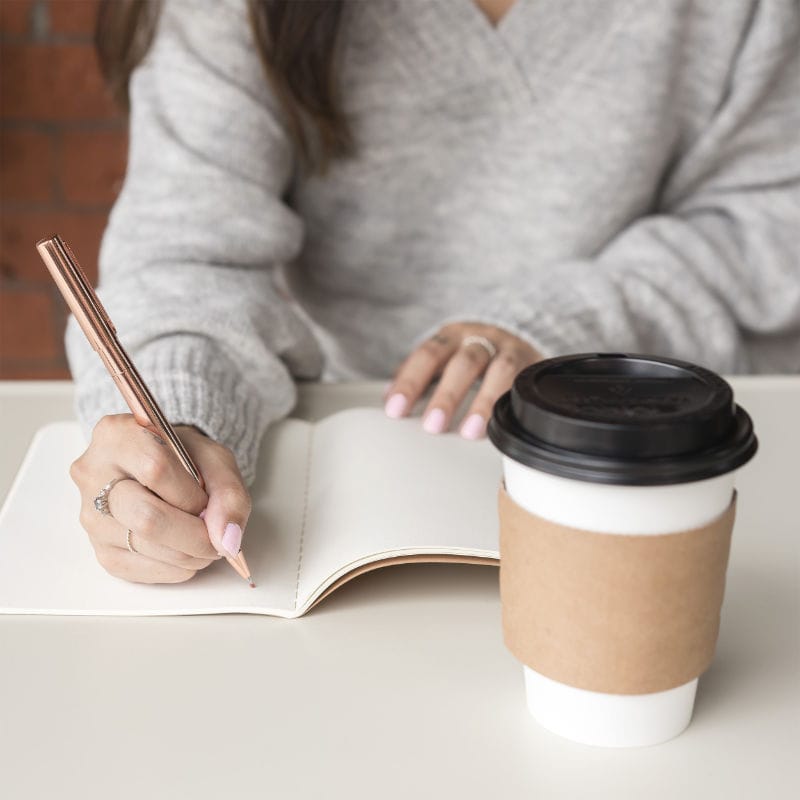 Woman writing in a journal and drinking coffee